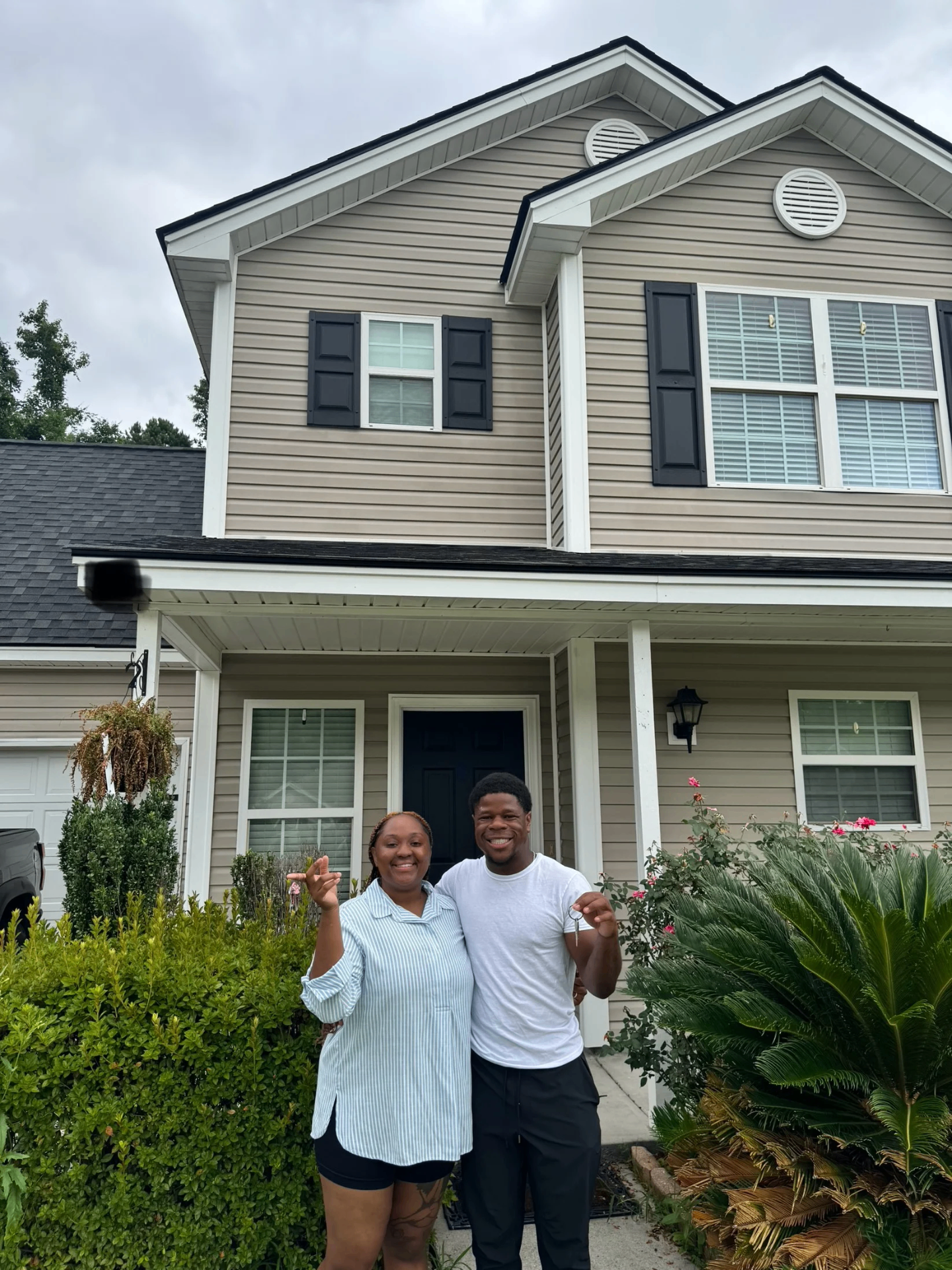 Happy Army veteran couple Jayana B celebrating in front of their new home after successful VA loan approval with Valor Home Mortgage